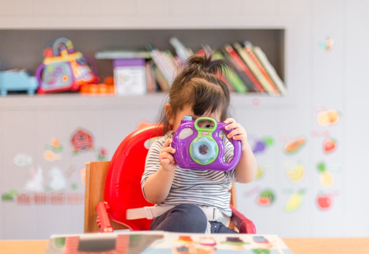 A young child playing with a colorful toy camera